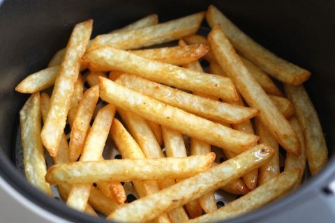 Crispy french fries in an air fryer basket, not overcrowded.
