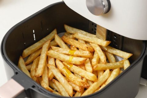 Golden french fries arranged perfectly in an air fryer basket.
